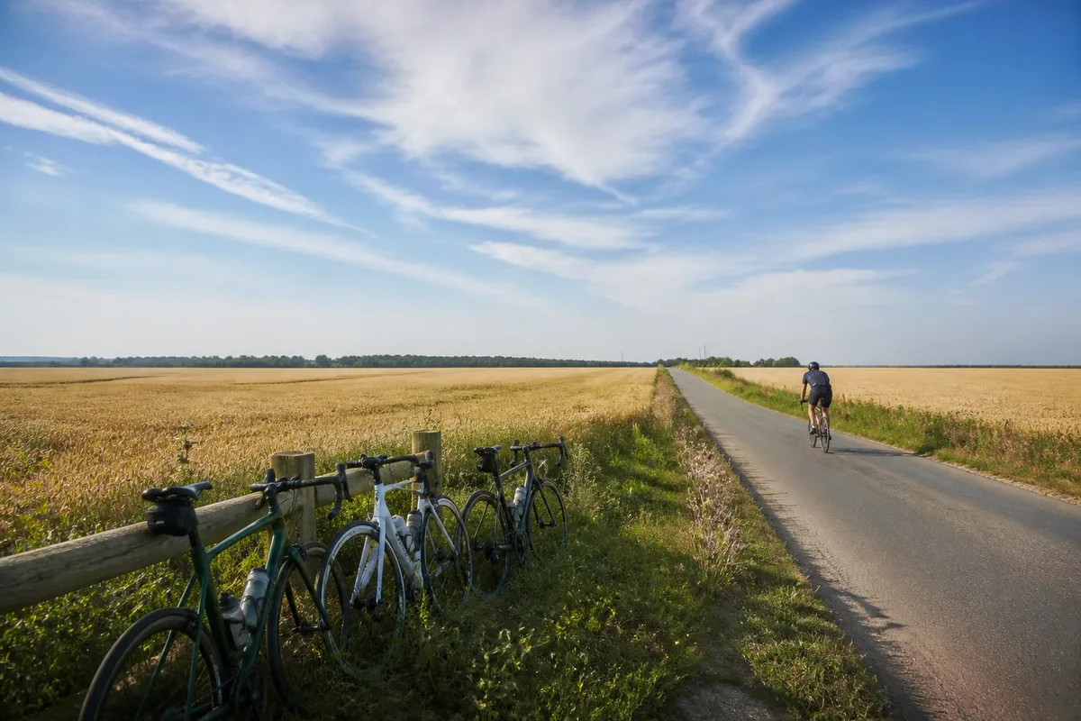 Cycliste roulant à allure régulière sur une longue route de campagne